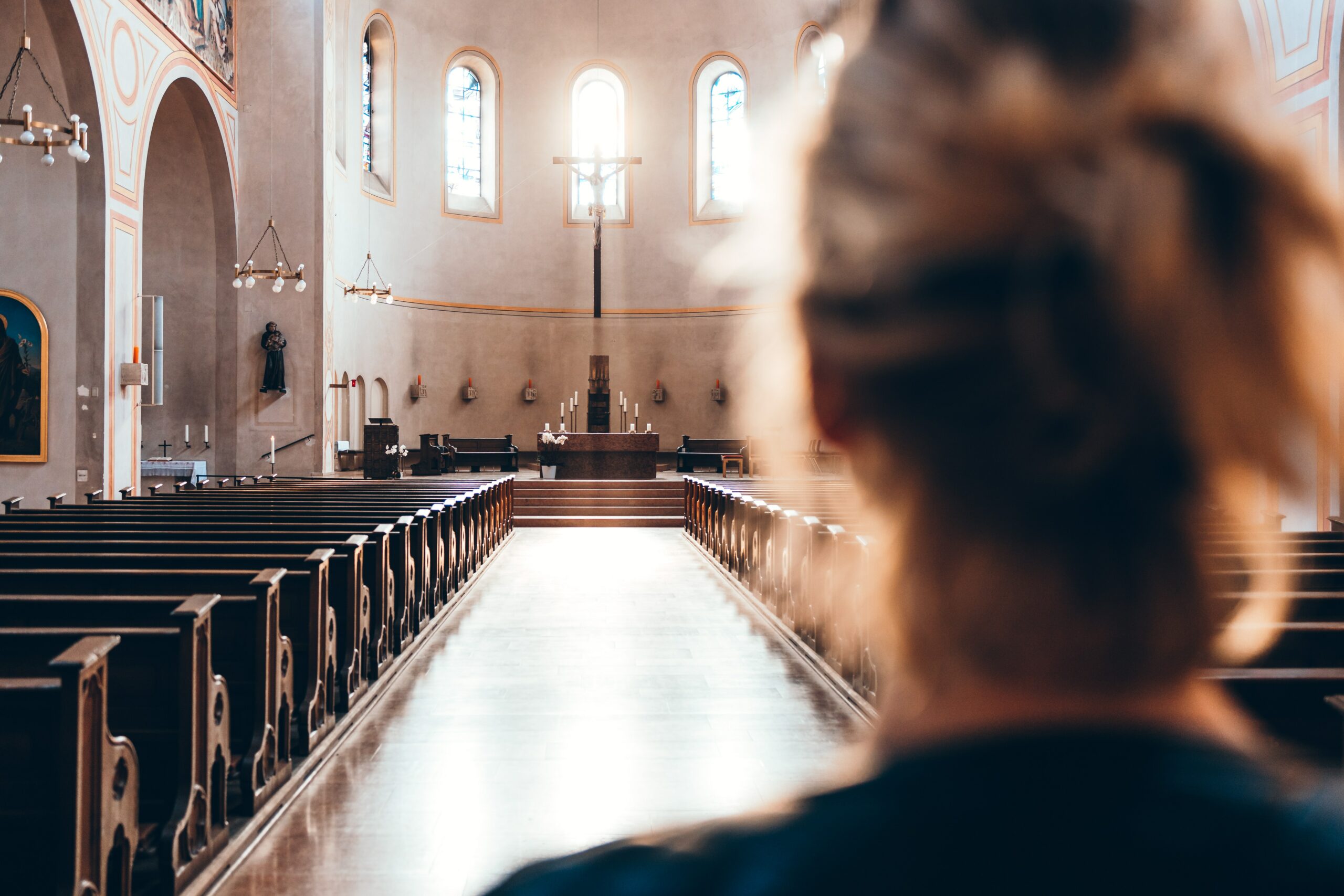 Frau von hinten, die in einer Kirche steht, Blick auf den Altar