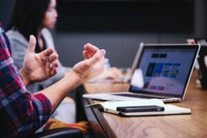 Mitarbeitende sitzen vor einem aufgeklappten Laptop