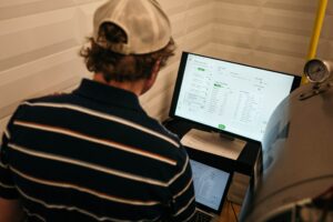 Junger Mann (von hinten) sitzt vor einem Computerbildschirm